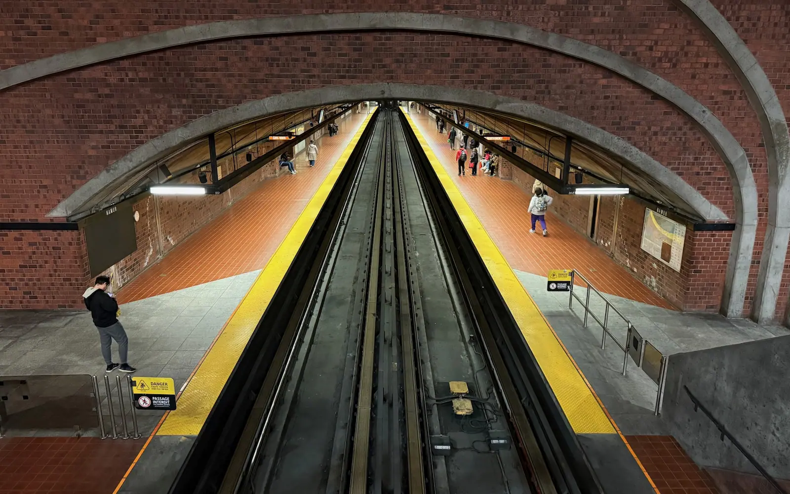 Looking towards the platforms at Namur Station on the Montreal Metro network. No trains are at the station, but passengers are waiting.